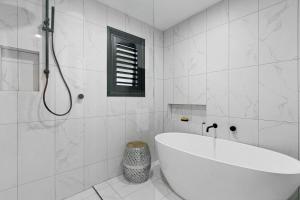 une salle de bain blanche avec une baignoire et une douche dans l'établissement Modern Tranquility in the heart of Tanunda, à Tanunda