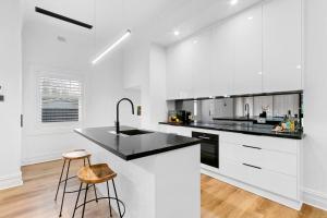 une cuisine avec des armoires blanches et un comptoir noir dans l'établissement Modern Tranquility in the heart of Tanunda, à Tanunda 17 autres photos