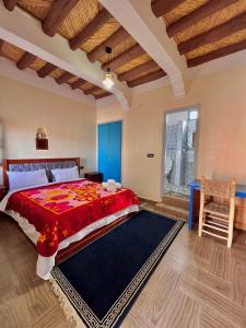 ein Schlafzimmer mit einem großen Bett mit einer roten Bettdecke in der Unterkunft Riad Lina tafraout 