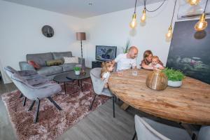 Ein Mann und zwei Kinder sitzen an einem Tisch im Wohnzimmer in der Unterkunft Vakantiepark BreeBronne in Maasbree + 22 Fotos
