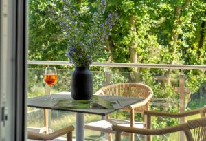a table with a vase of flowers and a glass of wine at Apartment C6 - mit großem, überdachten Südbalkon im "Pine Hill Resort" in Zirchow