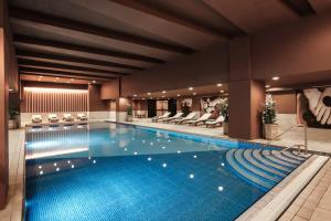 a large swimming pool in a hotel with chairs at voco Malta by IHG in St. Julianʼs
