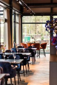un restaurant avec des tables et des chaises et de grandes fenêtres dans l'établissement Kampeerdorp de Zandstuve - Kindvriendelijke Vakantiepark, à Rheeze