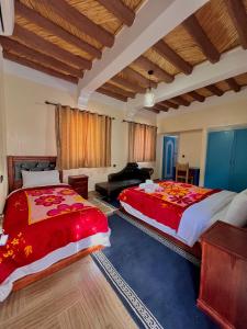 2 Betten in einem großen Zimmer mit Holzdecken in der Unterkunft Riad Lina tafraout 