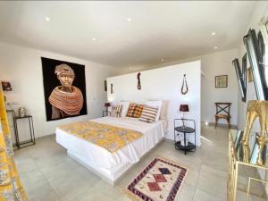 ein Schlafzimmer mit einem Bett und einem Gemälde an der Wand in der Unterkunft Villa Blanche in Ngaparou