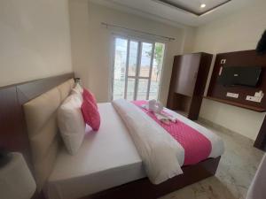 Hotal Glory Ganga في حاريدوار: غرفة نوم مع سرير مع دمية دب عليها +صورتان