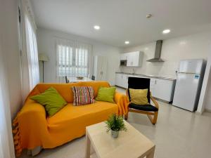 a living room with an orange couch and a kitchen at Geysotur Torrox Playa Apartamentos in Torrox