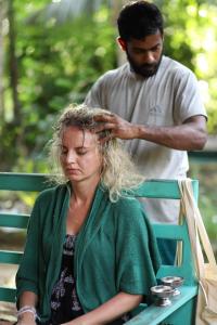 Eine Frau sitzt auf einer Bank, während ein Mann ihr die Haare färbt. in der Unterkunft Sirilaka Wedagedara in Alutwala