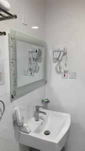a white bathroom with a sink and a mirror at العييري ريزيدنس in Dammam