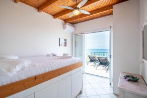 een slaapkamer met een bed en een balkon met uitzicht op de oceaan bij Seaside Holiday House by elite in Psarou