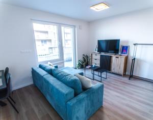 a living room with a blue couch and a television at Doctor's Cosy Apartment in Lamač
