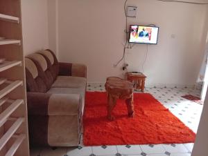 a living room with a couch and a table on a red rug at Humility - Olive in Naro Moru