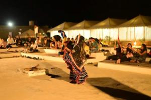 Una mujer está bailando frente a una multitud de personas. en Ozaki Desert Camp & Resort, en Jaisalmer