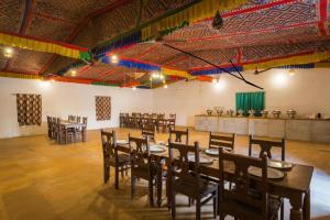 un salón de banquetes con mesas y sillas de madera en Ozaki Desert Camp & Resort, en Jaisalmer