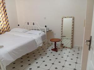ein Schlafzimmer mit einem Bett, einem Tisch und einem Spiegel in der Unterkunft Humility - Olive in Naro Moru + 5 Fotos