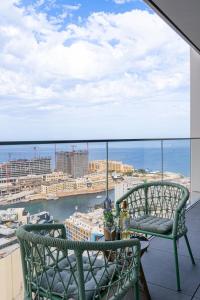 a balcony with two chairs and a view of the city at 21st Floor Sunset Apartment - Mercury Tower with Pool Access by Stays Uniq in St. Julianʼs