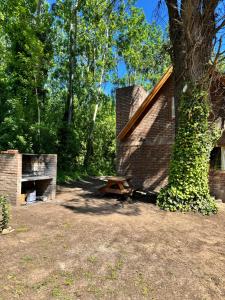 een picknicktafel naast een bakstenen gebouw met een boom bij La Rubina in Villa Ventana