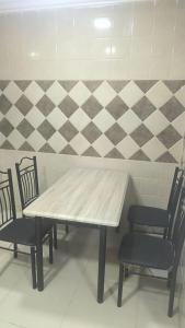 ein Tisch und Stühle in einem Raum mit gefliester Wand in der Unterkunft نجم الحضارة للشقق المخدومة in Al-Hasa