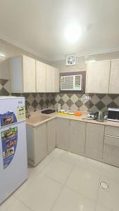 eine Küche mit weißen Schränken und einem weißen Kühlschrank in der Unterkunft نجم الحضارة للشقق المخدومة in Al-Hasa