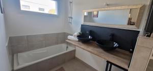 une salle de bain avec deux lavabos, une baignoire et un miroir dans l'établissement Jolie maison moderne à Séné à proximité du Golfe du Morbihan, à Séné 33 autres photos