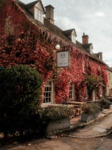 an ivy covered building with a sign on it at New Inn at Coln in Coln Saint Aldwyn