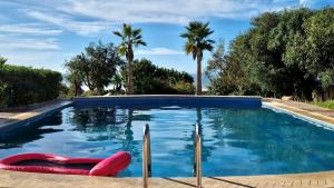une piscine avec des bouées rouges dans un jardin avec des palmiers dans l'établissement Dar Skalli Essaouira - Oase am Atlantik, à Aït Raïs Aomar 50 autres photos