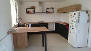 eine Küche mit einem weißen Kühlschrank und einem Holztisch in der Unterkunft Chambre chez l'habitant in Crach