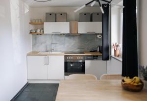 une cuisine avec des armoires blanches et une table en bois dans l'établissement Schöne Designer-Wohnung im Mangfalltal, à Bruckmühl