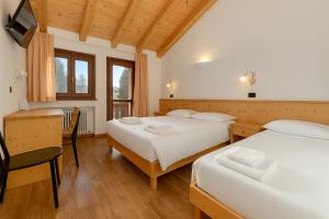 una camera da letto con due letti, un tavolo e delle sedie di Hotel Bleis a Ponte di Legno