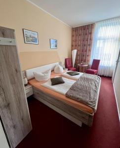 une chambre d'hôtel avec un lit et deux chaises dans l'établissement Villa HarzFokus - #Hotel#Pension#Frühstück, à Wernigerode