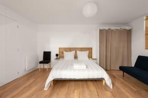 ein weißes Schlafzimmer mit einem Bett und einer Couch in der Unterkunft Le Loft du Castel Bas - Pause au cœur du Tarn in Castelnau-de-Montmiral