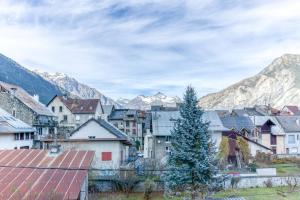 une ville avec un arbre de Noël en face des montagnes dans l'établissement Le Cosy Lodge, à Le Bourg d'oisans