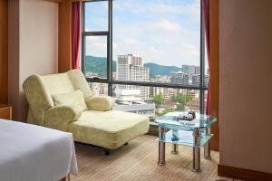ein Hotelzimmer mit einem Stuhl und einem großen Fenster in der Unterkunft Nanyang King's Gate Hotel--Free Shuttle Service to Canton Fair in Guangzhou