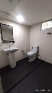 a bathroom with a white toilet and a sink at EVOKE Hostel Mirissa in Mirissa