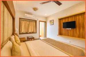 普里SEA VIEW from ROOF -Subrata Sarkar Road A1 Premium Lagoon Luxuary Hotel Near Jagannath Temple - 500M Sea Beach - Swimming Pool - Restaurant- Breakfast Included And Parking Facilities - Top Rated Four Star Hotel In Puri的一间卧室，里面有一张床和一台平板电视