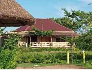 a house with a red roof and a person standing in front of it at LIMAS Camp Mikumi in Mikumi