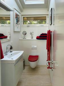 La salle de bains est pourvue d'un lavabo blanc et d'un tabouret rouge. dans l'établissement Sommerhus Med Sjæl Få Skridt Fra Vandkanten, à Martofte