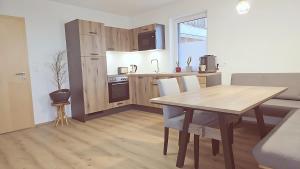 兰格尔斯道夫Konis Ferienwohnung的厨房以及带木桌、桌子和椅子的用餐室。