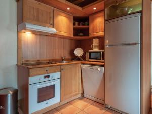 eine Küche mit Holzschränken und einem weißen Kühlschrank in der Unterkunft Chalet montagnard à Pra Loup avec 3 chambres et cheminée - FR-1-165A-47 in Uvernet