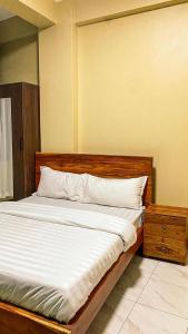 ein Bett mit weißen Laken und Kissen in einem Zimmer in der Unterkunft Wyne's Hotel in Mbale