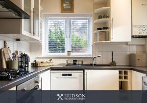 a kitchen with white cabinets and a sink and a window at Home with Rear Terrace in Ironbridge in Ironbridge +8 photos