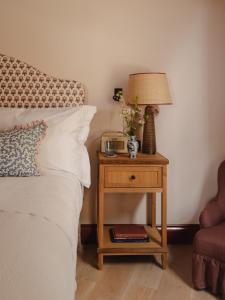 ein Bett mit einem Nachttisch mit einer Lampe und einem Tisch mit einem Nachttisch in der Unterkunft Luxury Apartment with Roof Terrace - Cotswolds in Stow on the Wold