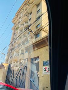 Een hoog gebouw is te zien door het raam van een bus. bij NK Plaza in Nairobi