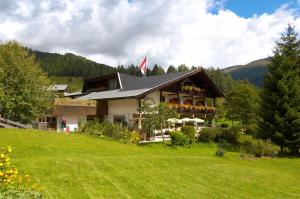 a house on a hill with a green field at Schi- und Wanderhotel Berghof in Bad Kleinkirchheim