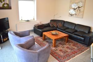 a living room with a black leather couch and a coffee table at Ferienhaus Meerzeit in Dornum