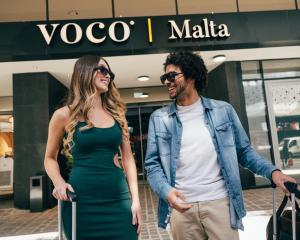 a man and a woman standing in front of a store at voco Malta by IHG in St. Julianʼs