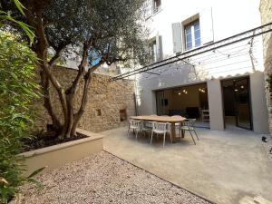 Chez Louise et Léo في إج مورت: فناء مع طاولة وشجرة بجوار مبنى