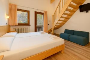 a bedroom with a large bed and a blue couch at Hotel Bleis in Ponte di Legno