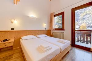 a bedroom with a large white bed and a window at Hotel Bleis in Ponte di Legno