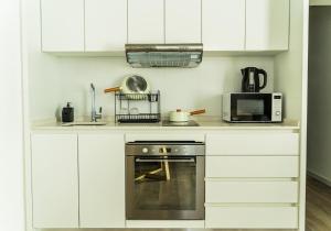 a white kitchen with a stove and a microwave at RentUp Suites Palmas Park Buenavista in Victoria